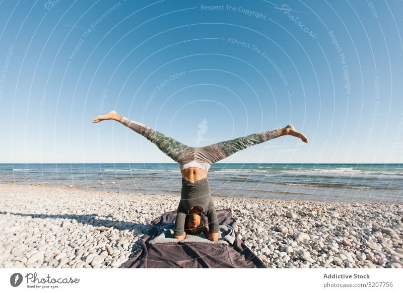 Sportliche Frau, die am Strand Yoga-Haltung ausübt praktizieren Kopfstand positionieren Erholung Übung schön Seeküste Fitness Freizeit Training meditieren