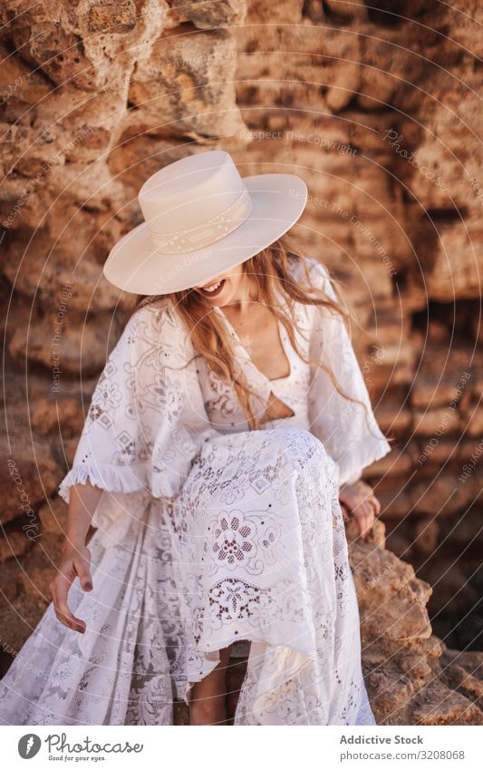 Prachtvolle Frau sitzt an einer zerstörten Mauer Mode stylisch trendy glamourös Model Kleid weiß Spitze Kleidung Wand ruiniert Stein jung Person schön hübsch