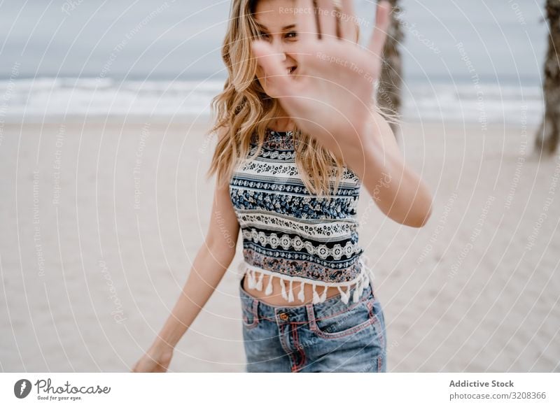 Glückliche Frau posiert am Sandstrand deckend Gesicht Hand Strand Fröhlichkeit Sperrfläche modisch glamourös Sommer Urlaub Feiertag jung Person attraktiv schön