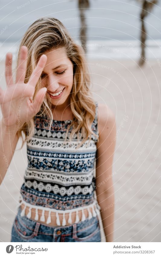 Glückliche Frau posiert am Sandstrand deckend Gesicht Hand Strand Fröhlichkeit Sperrfläche modisch glamourös Sommer Urlaub Feiertag jung Person attraktiv schön