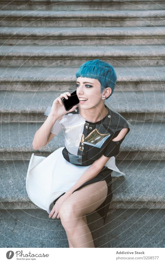 Junge futuristische Frau mit Smartphone auf der Treppe alternativ Kleid trendy Straße urban benutzend hören Subkultur Lächeln Mode Freitreppe blaue Haare