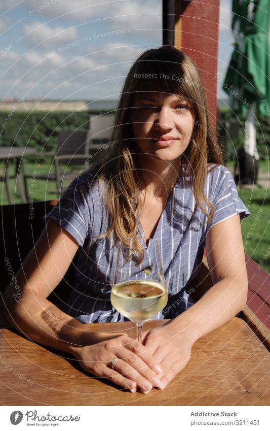 Junge Frau trinkt Wein in der Laube trinken aussruhen Kälte Urlaub Glas Tisch sonnig Lächeln Landschaft nida Litauen hölzern jung Erwachsener Kleid friedlich