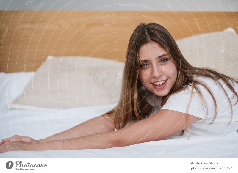 Schöne Frau in weißem T-Shirt, die sich auf dem Bett entspannt und in die Kamera schaut Ausflugsziel Abenteuer Urlaub jung Person schön attraktiv hübsch Barfuß