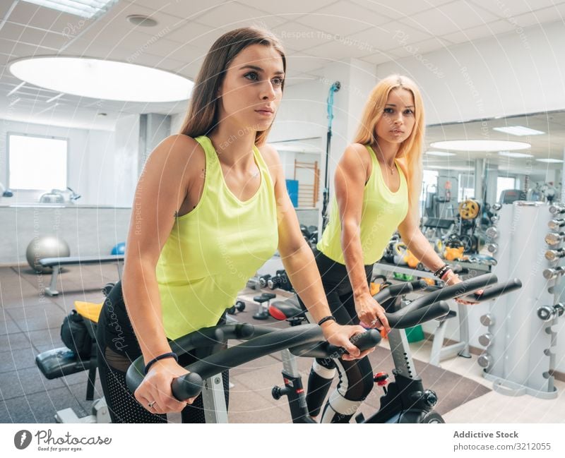 Junge Frauen üben gemeinsam an Maschinen Herz Fitnessstudio Spinning Fahrradfahren modern Athlet Übung Zusammensein Training Sport Team Aufwärmen Kraft jung