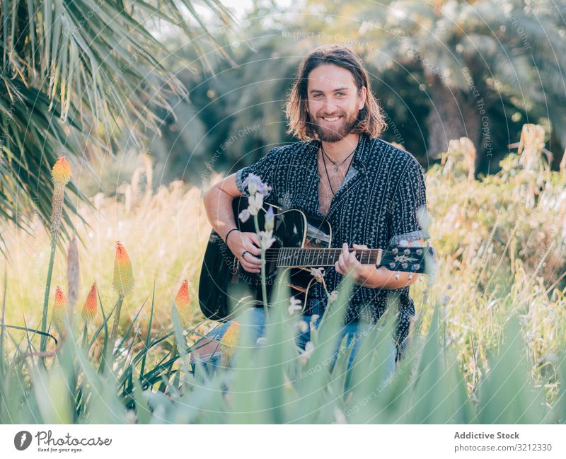 Hipster-Mann auf der Wiese mit Gitarre Musiker Sitzen Dschungel Spielen Abenteuer Ausflug Sommer Lifestyle besinnlich männlich akustisch jung Entertainment