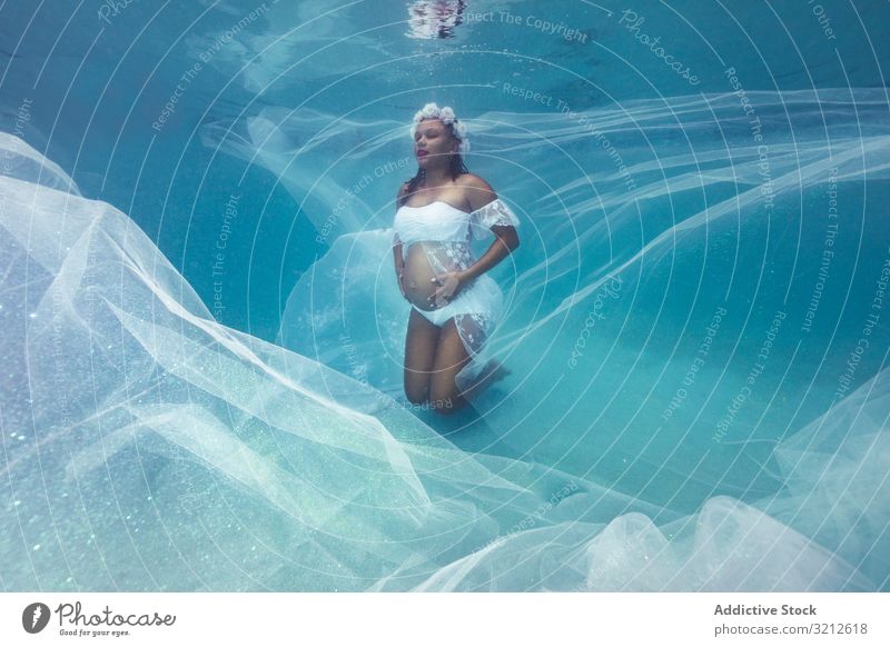 Schwangere Frau in Kranz und weißem Kleid unter Wasser schwanger geblümt natürlich Reinheit Harmonie unschuldig Totenkranz sinnlich Mutter Frieden Liebe