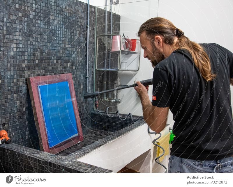 Künstlerin bereitet Siebdruck für Serigraphie vor Werkstatt drucken Bildschirm vorbereiten erschaffend Mann blau Hobby Staffelei Farbe Zeichnung männlich