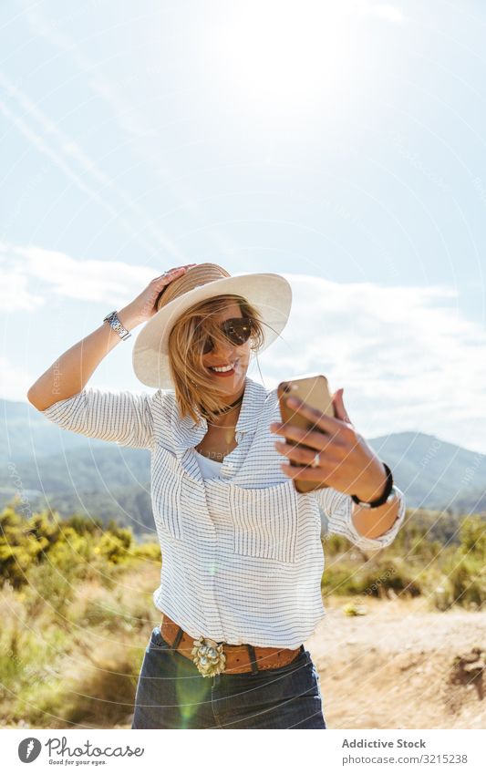 Junges Mädchen lächelt beim Blick auf ihr Smartphone Frau Glück Telefon Sonnenuntergang benutzend Menschen Mobile Hut Sonnenbrille jung klug Kaukasier Person