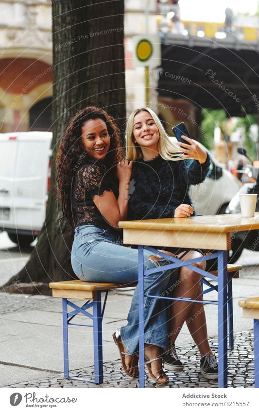 Freunde nehmen Selbstgefälligkeit in Straßencafé Frau Café reden Berlin schön Lächeln Glück Zusammensein Freizeit Genuss Restaurant rassenübergreifend hübsch