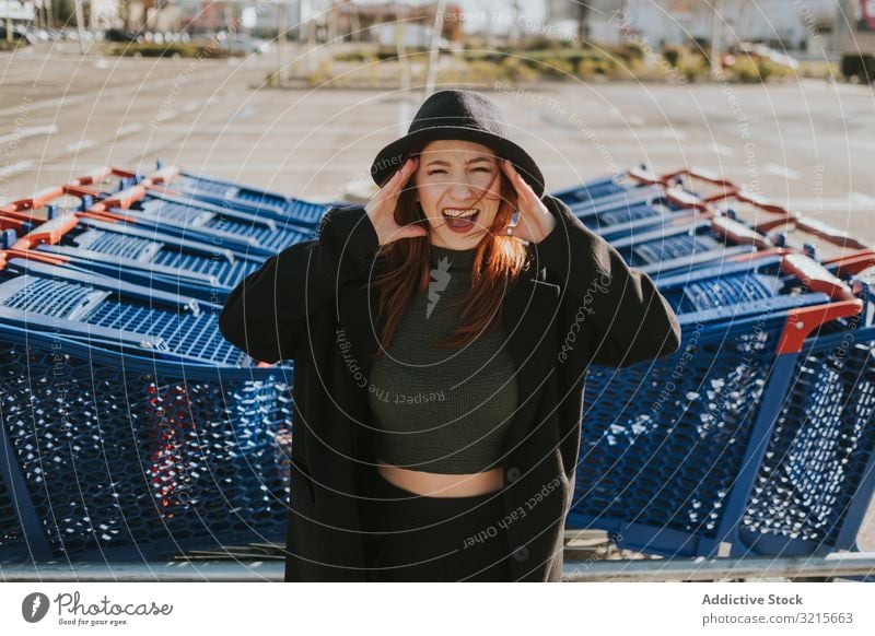 Frau schreit auf Parkplatz mit Einkaufswagen attraktiv jung schön lässig klug modern Freude aufgeregt Rotschopf hübsch Vergnügen stylisch Handwagen kaufen