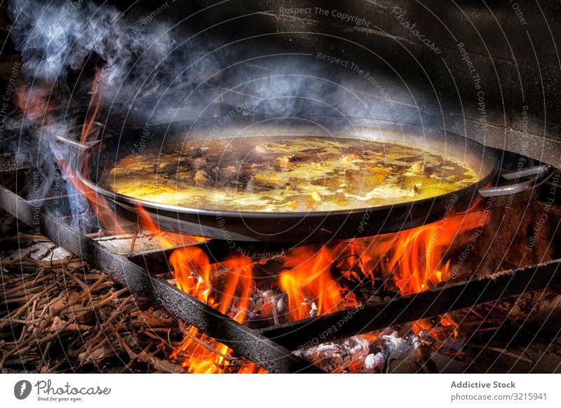 Verfahren zum Kochen von Paella auf Feuer Reis Essen zubereiten Prozess Küche Hinzufügen Spanisch traditionell Lebensmittel Hähnchen Brühe Flamme Pfanne bügeln