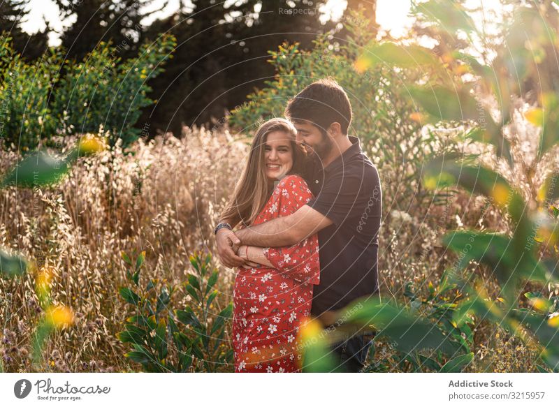 Junges glückliches Paar umarmt sich in schönem Garten umarmend schwanger Mann Frau Zärtlichkeit Park Glück erwartend Liebe Partnerschaft Zusammensein Liebhaber