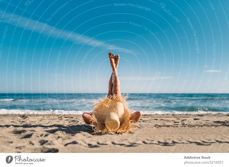 Frau mit großem Hut am Sandstrand liegend schlank Bräune Strand sandig Wasser attraktiv Sommer Freizeit sportlich Tierhaut Körper Seeküste wellig bedeckt