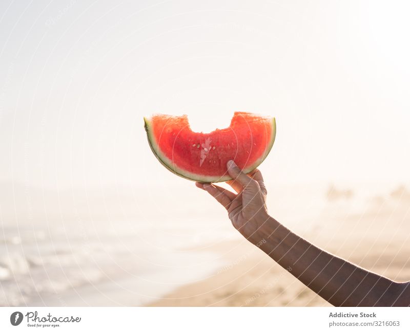 Hand einer Person, die eine rote Wassermelone hält Frucht Melonen Lebensmittel Strand sandig saftig geschmackvoll Snack Sommer Essen Seeküste Lifestyle Urlaub