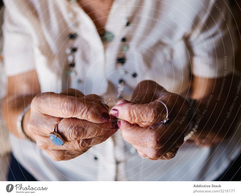 Ältere Frau mit Fäden zu Hause sitzend gealtert Faser stricken heimwärts Erfahrung Weisheit Großmutter Hobby handgefertigt Aufmerksamkeit Großeltern Generation