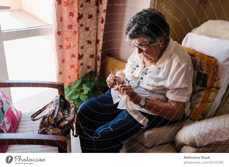 Ältere Frau nimmt Strickwerkzeuge zu Hause mit gealtert Garn Korb heimwärts Erfahrung Weisheit Großmutter Hobby handgefertigt Aufmerksamkeit Großeltern