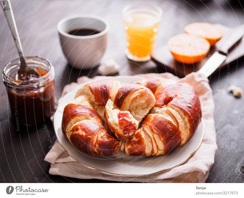 Frühstück mit Croissant und Kaffee Lebensmittel Frucht Orange Teigwaren Backwaren Marmelade Getränk Heißgetränk Saft Teller Tasse Glas Messer Duft Essen