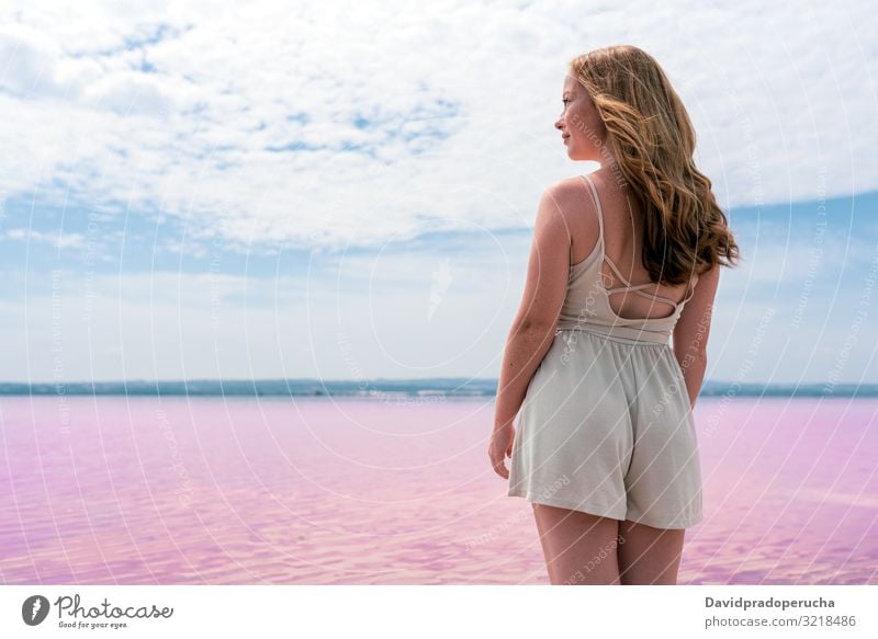 Rückenansicht von niedlichen Teenager Frau trägt Sommerkleidung auf rosa See alicante Spanien Strand schön Blauer Himmel Küste Färbung farbenfroh cool