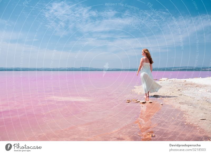 Rückansicht von niedlichen Teenager Frau trägt weißes Kleid zu Fuß auf eine erstaunliche rosa See jung Kochsalzlösung romantisch Tourismus Sommer Glück allein