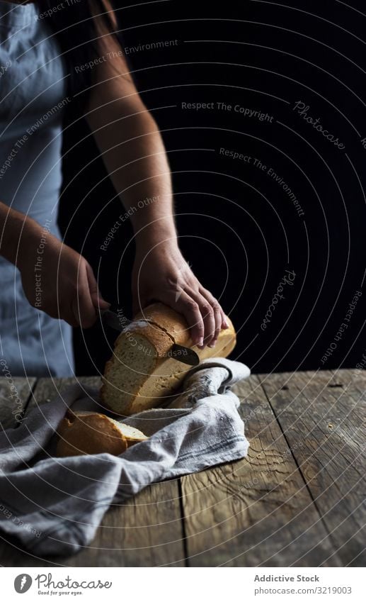 Getreidefrau beim Brotschneiden Frau geschnitten Tisch rustikal hölzern alt Messer Brotlaib frisch Serviette Lebensmittel Gesundheit Mahlzeit Mittagessen