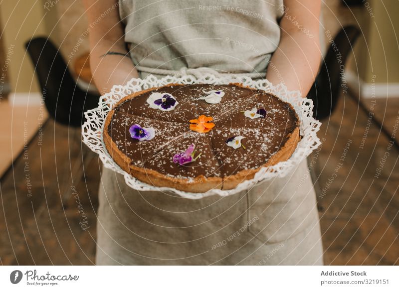 Brauner, mit Blumen geschmückter Kuchen in Frauenhänden Pasteten selbstgemacht süß Bäckerei Feinschmecker organisch Ernährung geschmackvoll appetitlich Hände