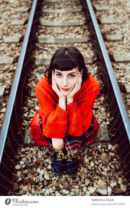 Frau sitzt auf Schwellen in der Mitte der Eisenbahn Koffer rot reisen stylisch grün Gepäck Natur schön Tasche Warten Freiheit Straße allein Ausflug Reise Buchse