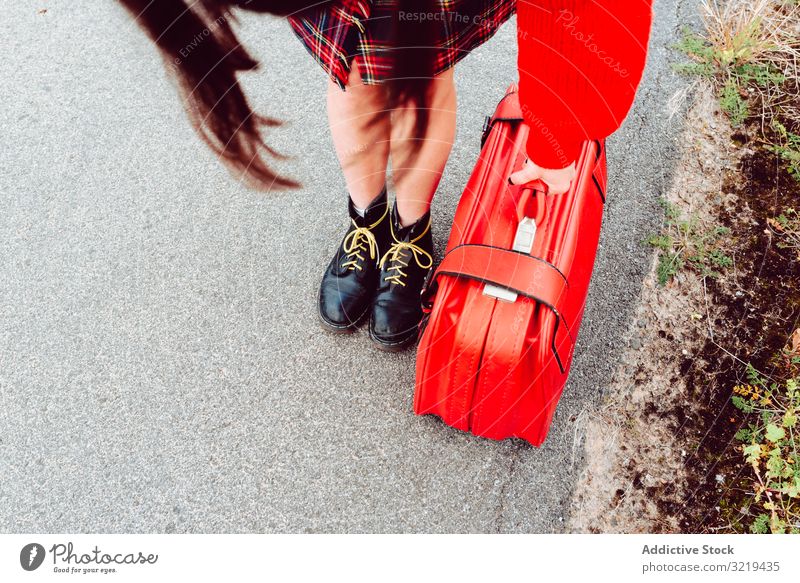 Frau in schicken Stiefeln mit rotem Koffer auf der Straße stehend Beine reisen stylisch Gepäck Natur schön Tasche Warten Freiheit allein Ausflug Reise Design