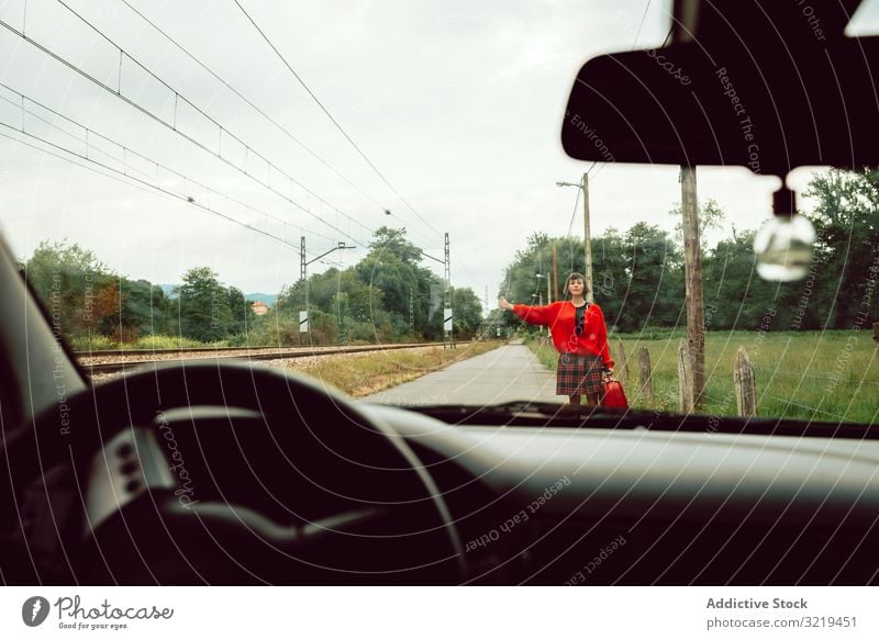 Frau im roten Pullover erwischt Auto auf der Straße automatischer Stopp Koffer gestikulierend PKW reisen stylisch Trampen Gepäck Natur schön Tasche Mode Warten