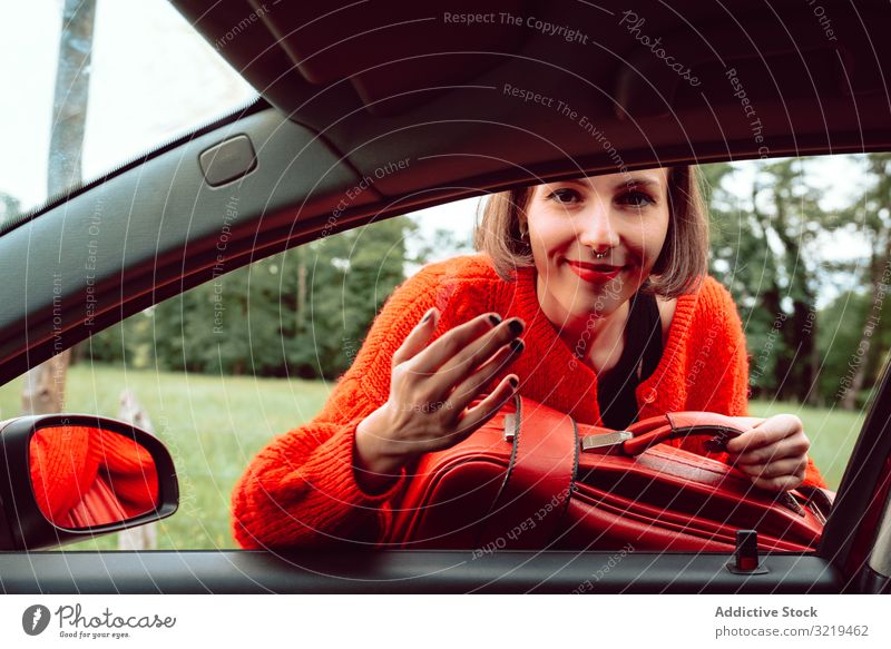 Frau stellt Koffer ins Autofenster rot PKW Straße reisen stylisch Gepäck Natur schön Tasche Mode Warten Freiheit allein Lächeln Ausflug Reise modern Fahrzeug