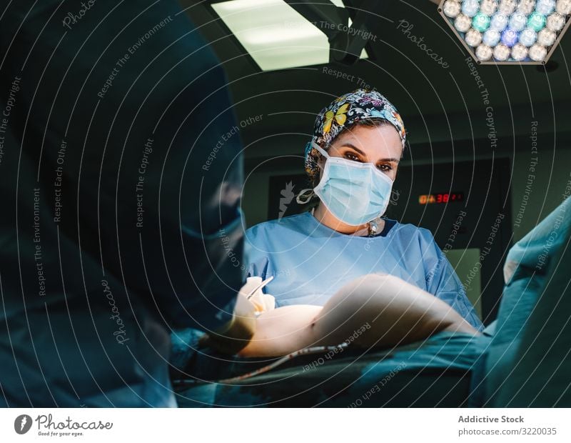Konzentrierte Chirurgin bei der Arbeit Frau Arzt Chirurgie Krankenhaus Operation Medizin Beruf Konzentration jung ernst achtsam chirurgisch Kleid blau