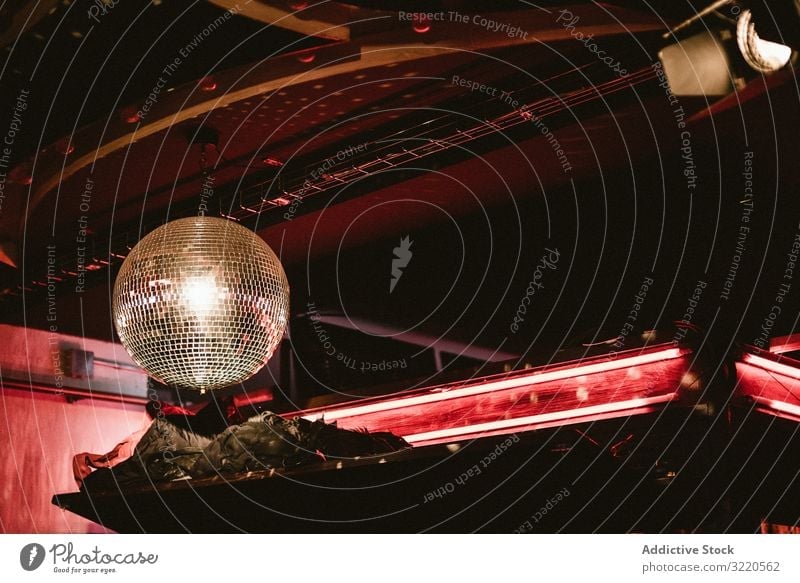 Deckenspiegelball in dunkler Keule mit rotem Licht Ball Club Nacht Knolle Disco neonfarbig Tanzen Tanzclub schwarz Beleuchtung hell glühend leuchtend