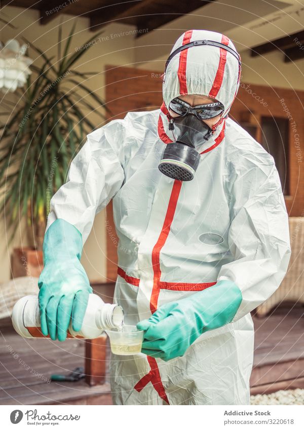 Mann im Anzug für Begasung schüttet Chemikalie in Tank Räucherapparat Gießen Atemwegserkrankungen Pestizid Gift Insekt Desinfektion Hof Mundschutz Pflanze