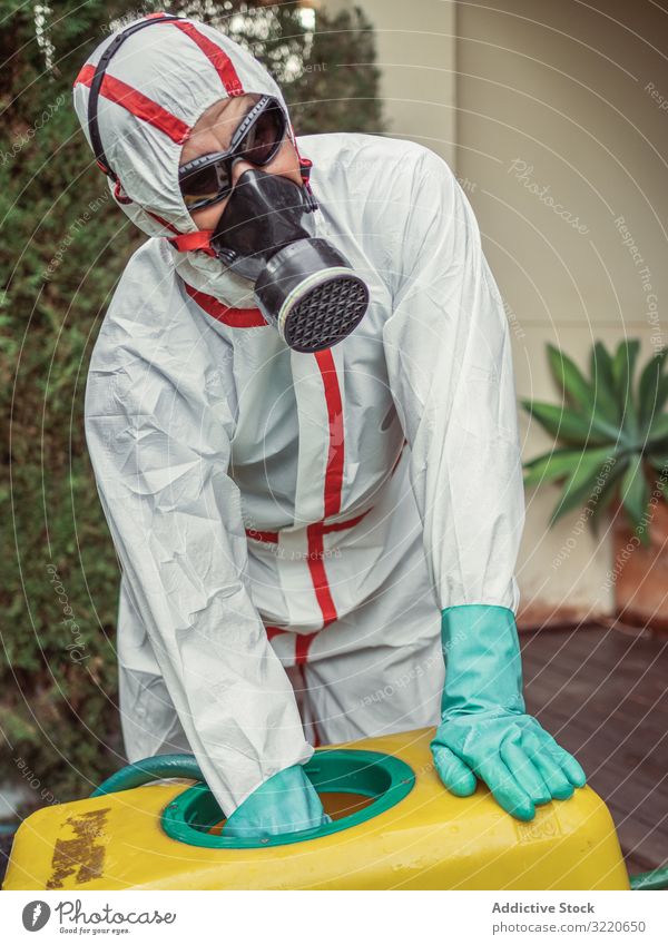 Spezialist in Uniform für Begasung hält gelben Wagen im Hof Mann Räucherapparat Atemwegserkrankungen Tank Pestizid Gift Insekt Desinfektion Mundschutz Pflanze