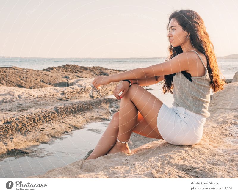 Hübsche trendige junge ethnische Frau am Strand bei Sonnenuntergang trendy modern lässig hübsch Inhalt Sonnenlicht Erwachsener Küstenlinie brünett attraktiv