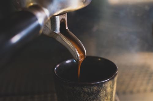 Espresso läuft aus einer Siebträger Kaffeemaschine in eine Espressotasse genießen siebträgermaschine Detailaufnahme Nahaufnahme kaffeezubereitung Koffein