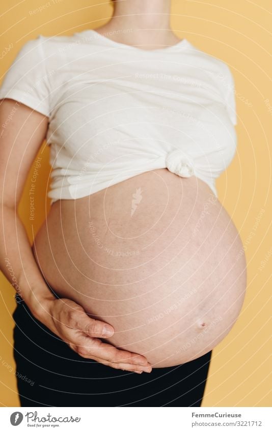 Schwangere Frau zeigt ihren Babybauch - neutraler Hintergrund feminin Erwachsene 1 Mensch 18-30 Jahre Jugendliche 30-45 Jahre Glück Haut bauchfrei Magen