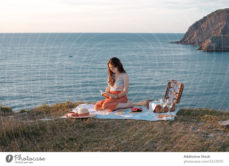 Frau liest auf Matte für Picknick am Meeresufer Buch Seeküste Strand Sommer lesen Freizeit Himmel MEER sich[Akk] entspannen Glas trinken Urlaub Sommerzeit