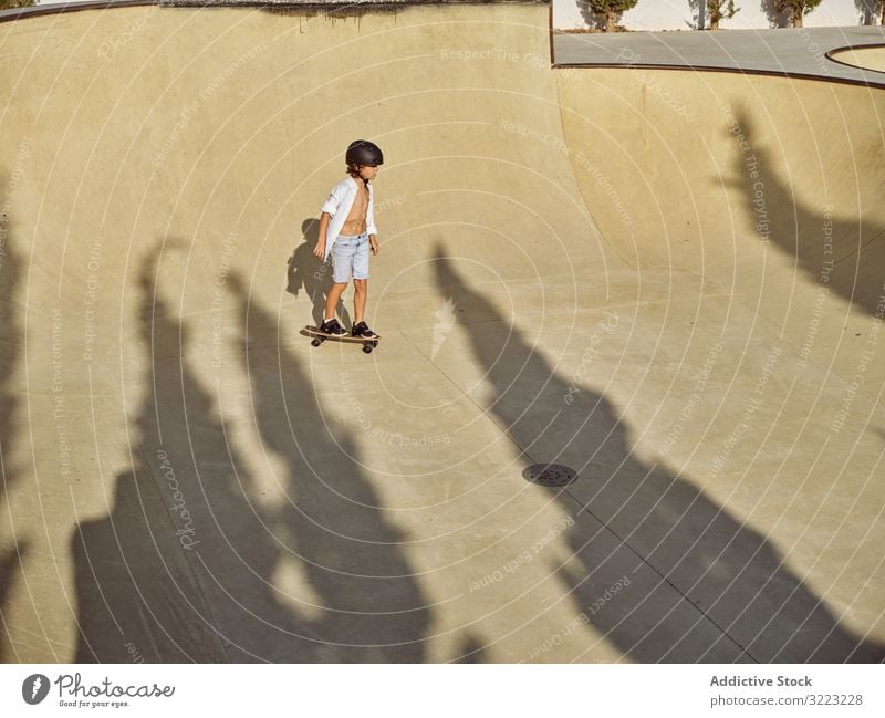 Kind mit Helm beim Skateboardfahren Skatepark Rampe Mitfahrgelegenheit Schutzhelm Sonnenlicht Sport Freizeit Hobby Junge jung anhaben Kindheit Sommer sonnig