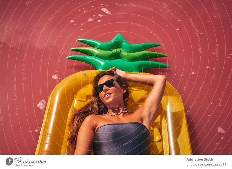 Verträumte Frau ruht auf aufblasbarer Matratze Kälte Lügen Sommer Luftmatratze verträumt rosa Reichtum einladend ruhen Sonnenbrille Badebekleidung Rote Lagune