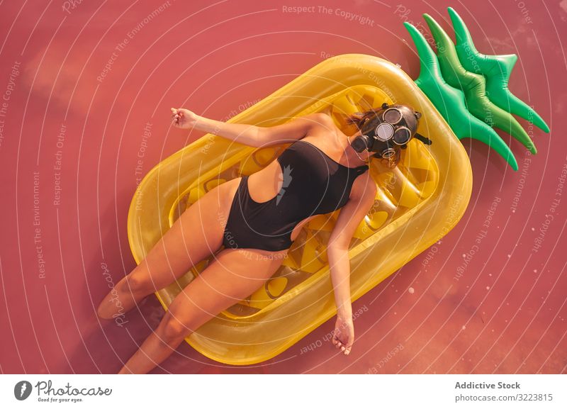Frau liegt auf Luftmatratze in rosa Seewasser Kälte Sommer Atemschutzgerät sich[Akk] entspannen Salz lebhaft friedlich ruhen Badebekleidung aufblasbar Ananas