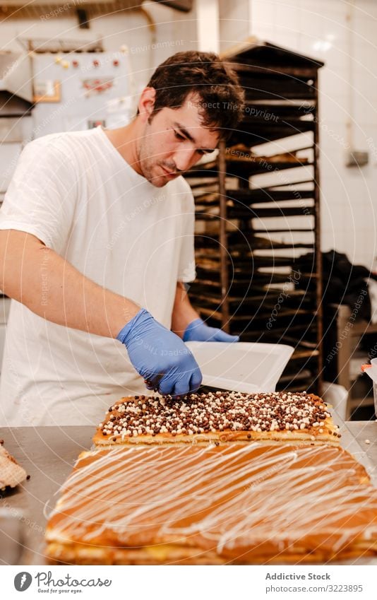 Anonymer Bäcker streut Streusel auf Gebäck Konditor Bäckerei Aufstrich Dekor Tisch Qualität Kuchen Vorbereitung Kleinunternehmen frisch Beruf traditionell