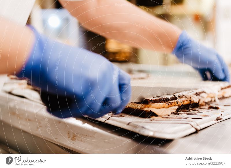 Getreide-Konditor, der Kuchen schneidet Bäckerei geschnitten Tisch Küche Arbeit Gebäck frisch Messer Ebene Handschuh Kleinunternehmen Lebensmittel Qualität