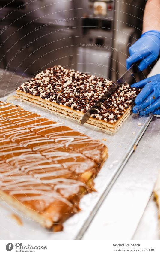 Anonymer Koch schneidet Kuchen auf dem Tisch an Konditor Bäckerei geschnitten Messer Gebäck süß frisch Küche Lebensmittel Vorbereitung Kleinunternehmen Mann