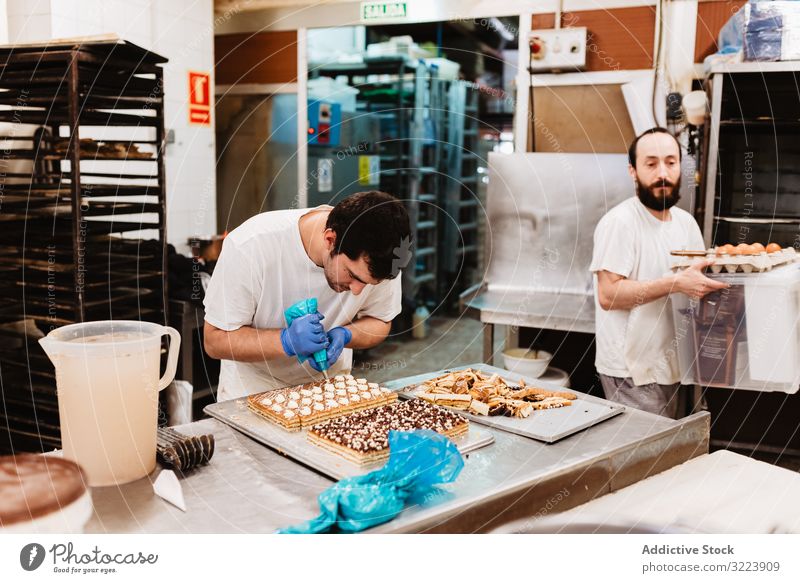 Erntebäcker, der Teig auf einem Blech auspresst Konditor Bäckerei Teigwaren drücken Tablett Keks Arbeit Küche Vorbereitung professionell Lebensmittel Papier