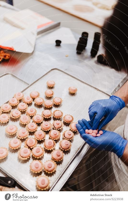 Anonymer Bäcker beim Dekorieren kleiner Kuchen Konditor Bäckerei Gebäck Arbeit Qualität Lebensmittel traditionell Mann Vorbereitung Inszenierung