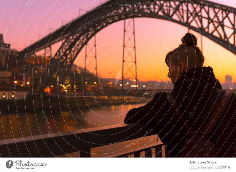Frau steht bei Sonnenuntergang auf der Böschung Tourist Stauanlage Großstadt Brücke Fluss sitzen Borte Wasser Architektur Wahrzeichen Himmel wolkenlos Abend