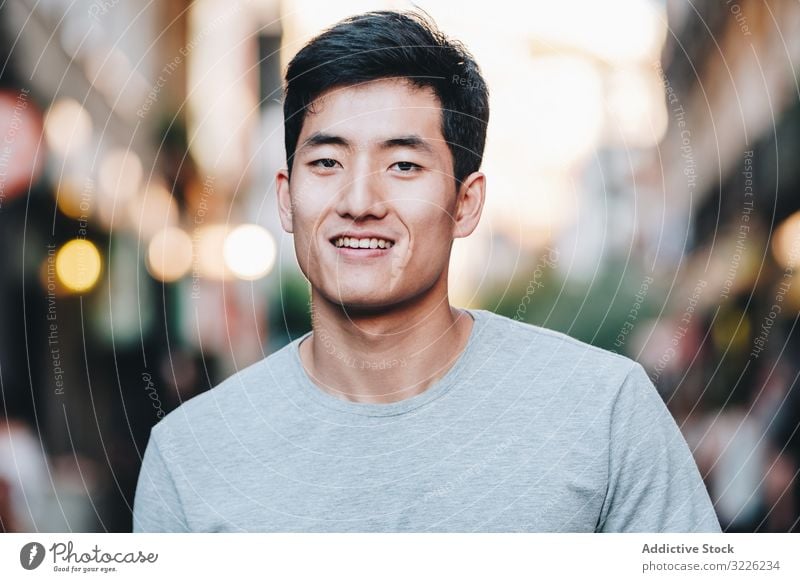 Selbstbewusster asiatischer Mann geht durch die Stadt selbstbewusst Straße Spaziergang Inhalt lässig T-Shirt gutaussehend urban schlendern Großstadt modern