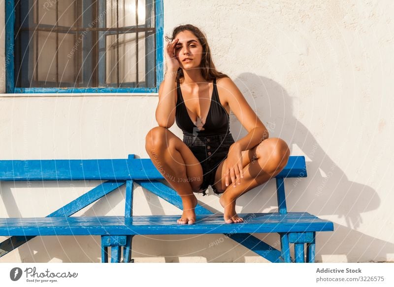 Junge Frau entspannt sich auf blauer Bank sich[Akk] entspannen Kniebeuge ruhen besinnlich Erholung stylisch lässig hübsch brünett schlank trendy traurig