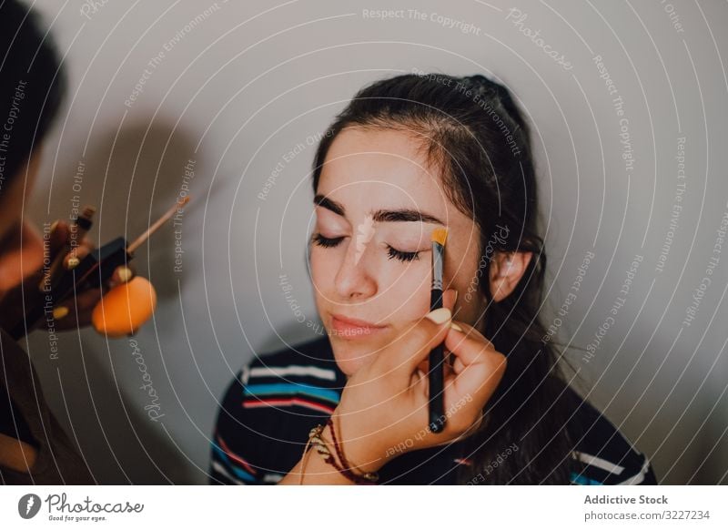 Junge Frau wird im Salon von Visagistin geschminkt Make-up visagiste Schönheit professionell Künstler Kosmetik Industrie Arbeit Beruf Gesicht jung Kunde Gerät