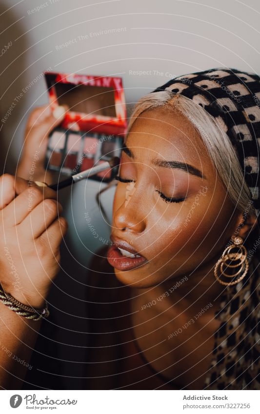 Afroamerikanische Frau wird im Studio geschminkt Make-up Lidschatten Schönheit professionell Künstler Kosmetik Industrie Klient Arbeit visagiste Beruf Gesicht